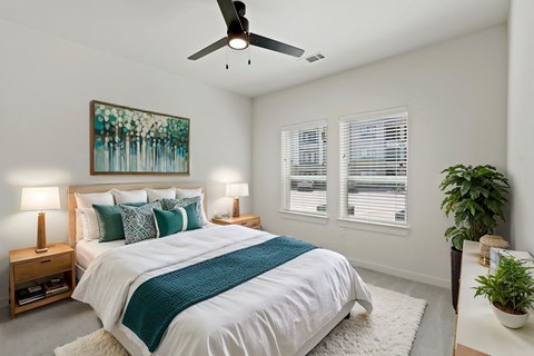 A bedroom with a large bed and a ceiling fan at Hudson at Pecan Creek Apartments, Texas