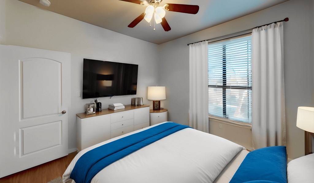 a bedroom with a bed and a ceiling fan and a tv