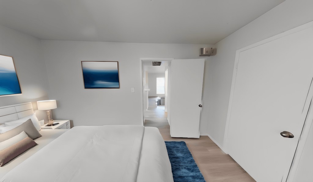 a white bedroom with a white bed and a blue rug