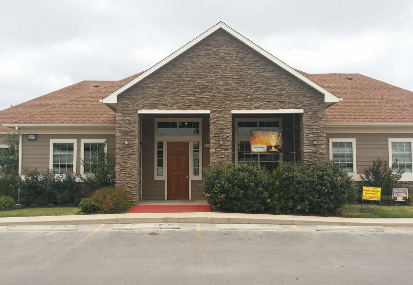 A building with a brown door and a sign in front of it.