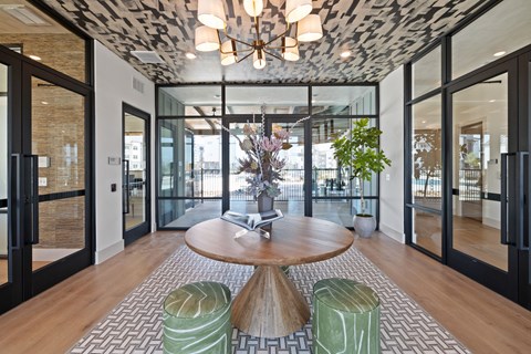 A modern living room with a round wooden table and green chairs.