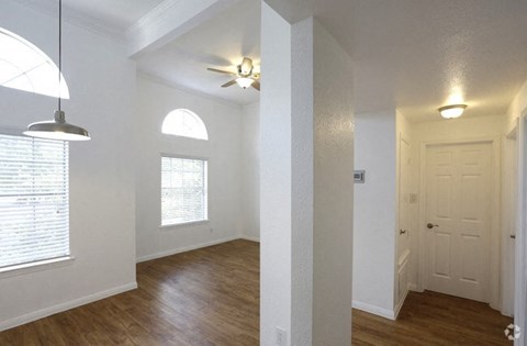 an empty living room with white walls and a ceiling fan