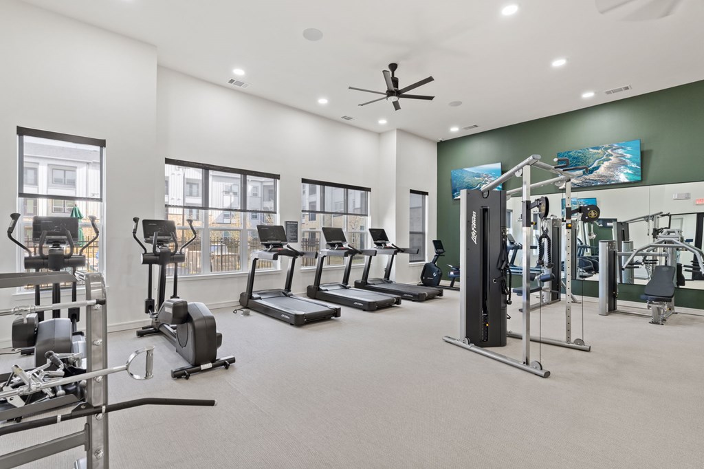 A spacious gym with a variety of equipment including treadmills, elliptical machines, and weight machines.