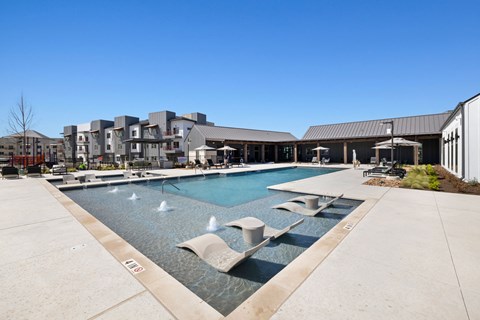 A large swimming pool with a fountain in the middle of it at Enclave Creedmoor Apartments, Creedmoor, TX, 78610