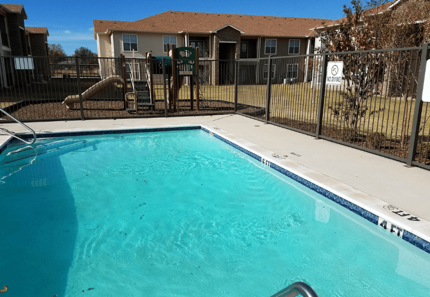 A swimming pool in a residential area with a fence around it.