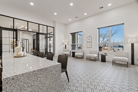 A spacious waiting area with a marble floor and black chairs at SOSA at Palo Alto Apartments, San Antonio, TX