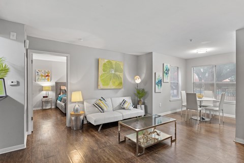 A living room with a white couch and a glass coffee table.