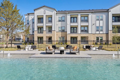 A modern apartment complex with a pool in front at Hudson at Pecan Creek Apartments, Denton, Texas