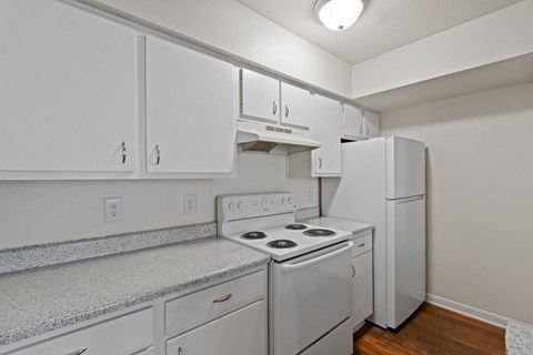 A white kitchen with a stove and a refrigerator.