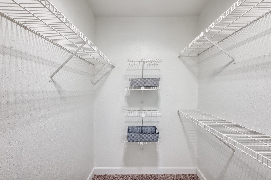 a walk in closet with white walls and shelves and two closets