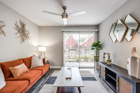 a living room with a orange couch and a sliding glass door