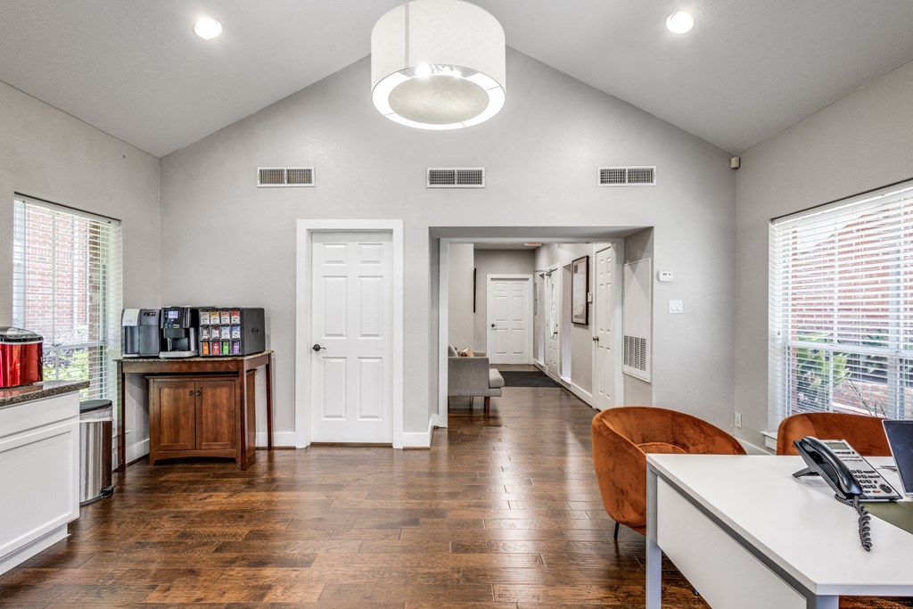 an office with a desk and a chair and a hallway with a door and windows