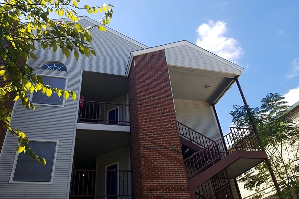 the exterior of a building with a balcony and a tree