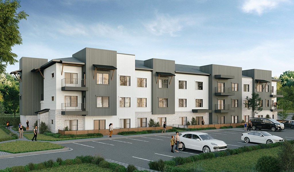A modern apartment complex with cars parked in front.