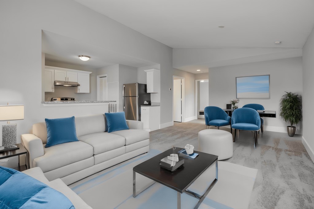 a living room with blue and white furniture and a kitchen