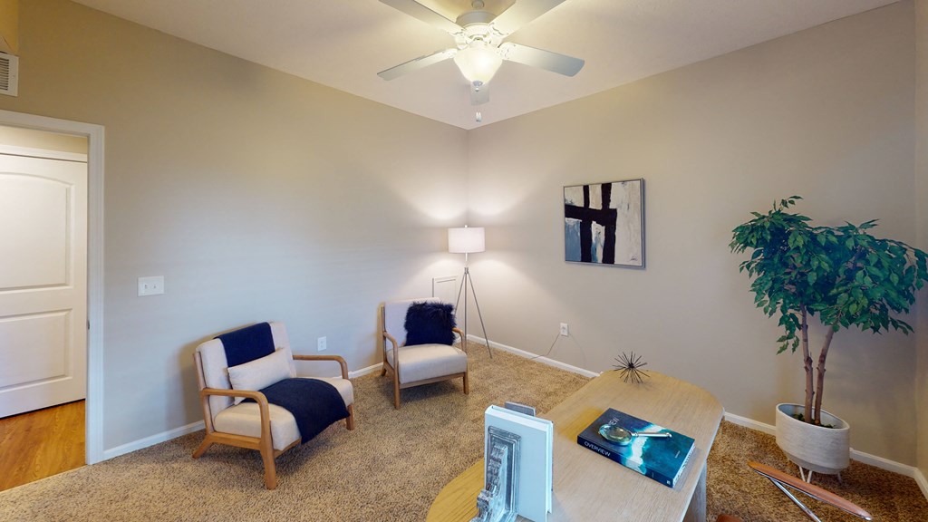 a living room with a ceiling fan and two chairs