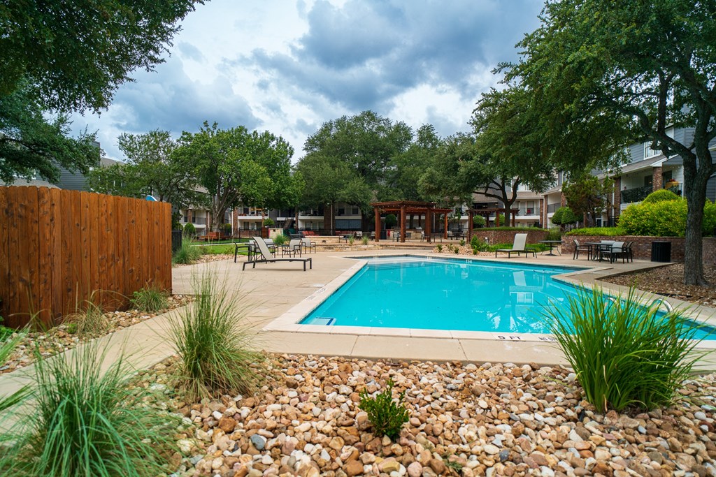 a swimming pool in a backyard with rocks and trees