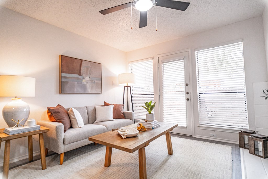 a living room with a couch and a coffee table and a ceiling fan