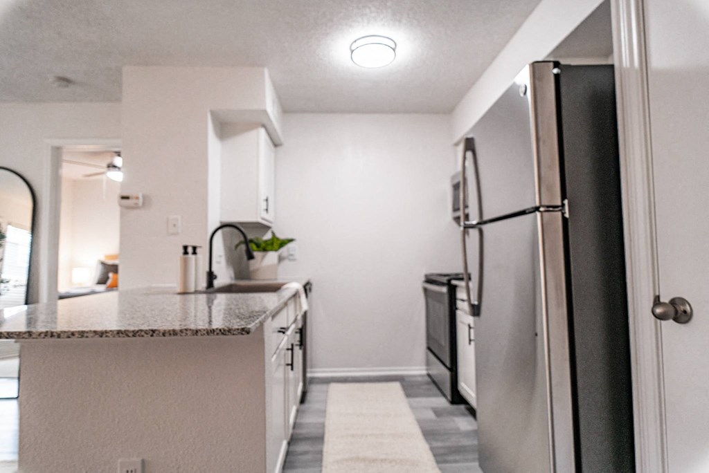 a kitchen with white cabinets and a black refrigerator