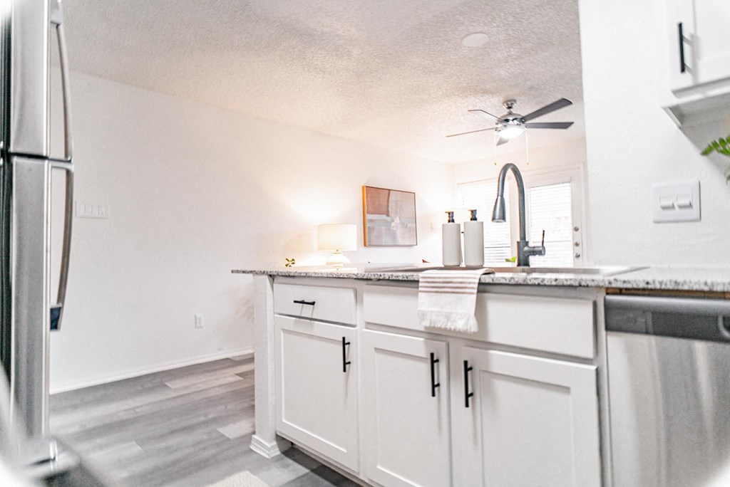 a view of a kitchen with white cabinets and a ceiling fan