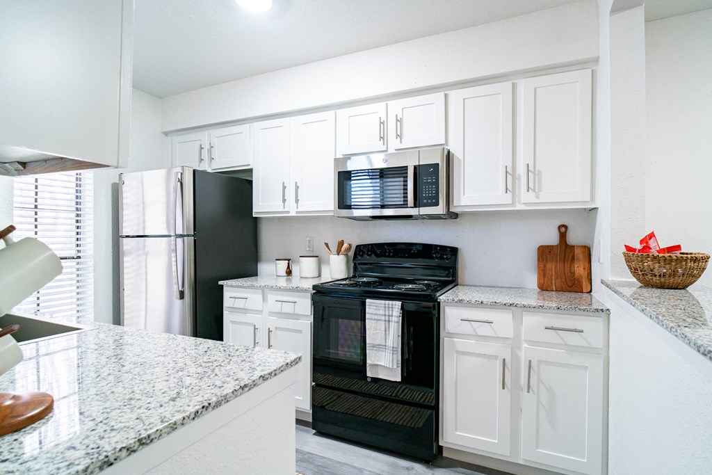 a kitchen with white cabinets and a black stove and refrigerator