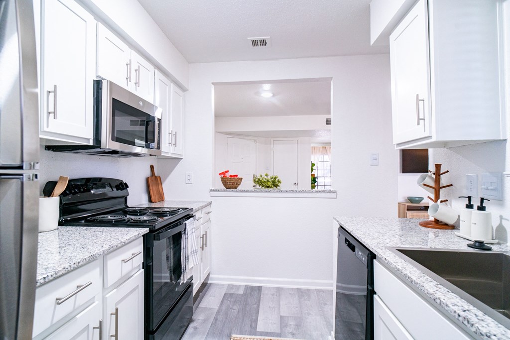 a white kitchen with black appliances and white cabinets