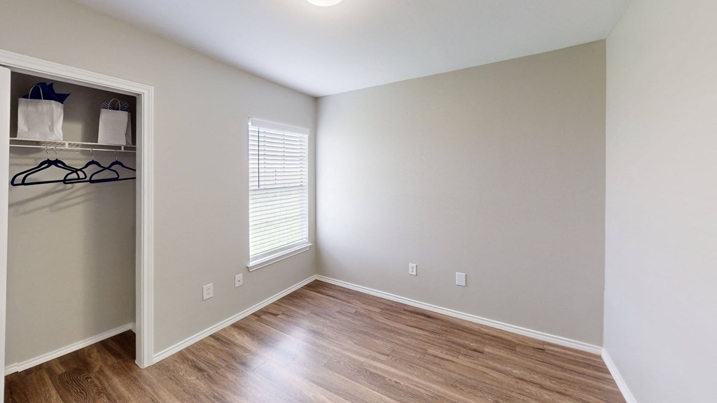 an empty room with wood flooring and a closet
