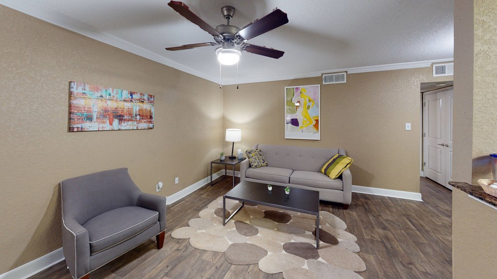 a living room with couches and a ceiling fan