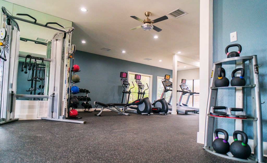 a home gym with weights and a ceiling fan