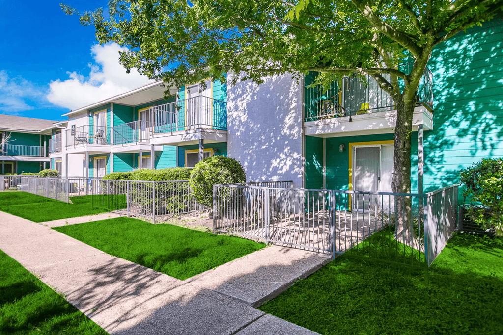an apartment building with a sidewalk and trees in front of it