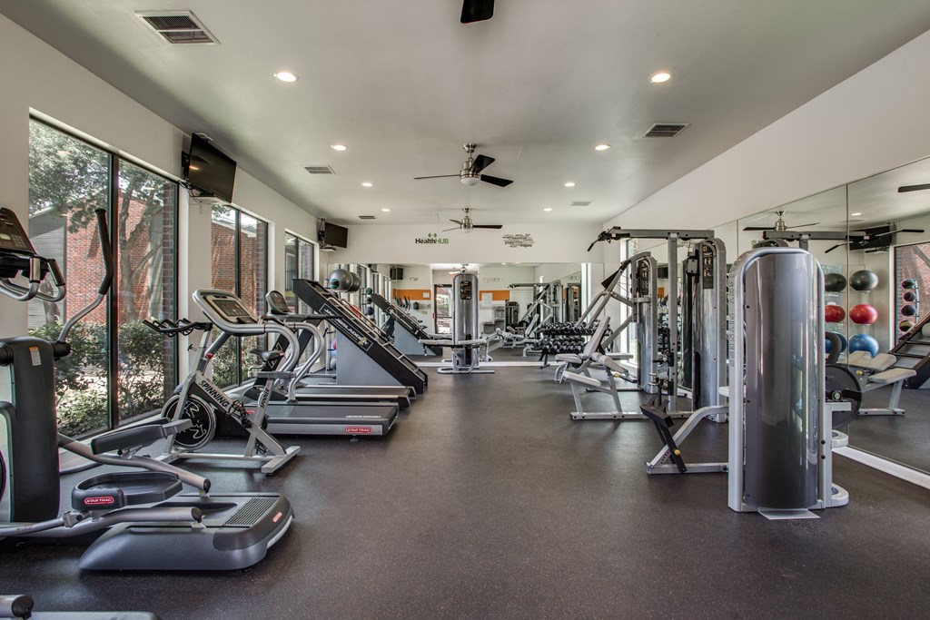 a gym with cardio equipment and windows in a building