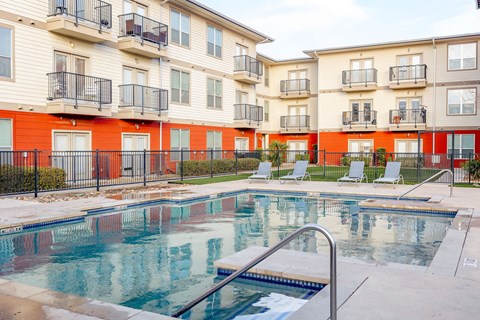 A swimming pool in front of a row of apartment buildings.