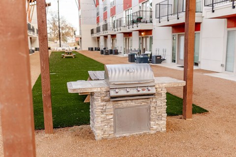 A BBQ grill is in the middle of a gravel area.