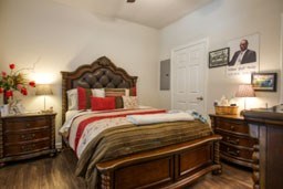 A bedroom with a large bed and a wooden dresser.