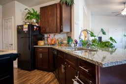 A kitchen with dark wood cabinets and a black refrigerator.