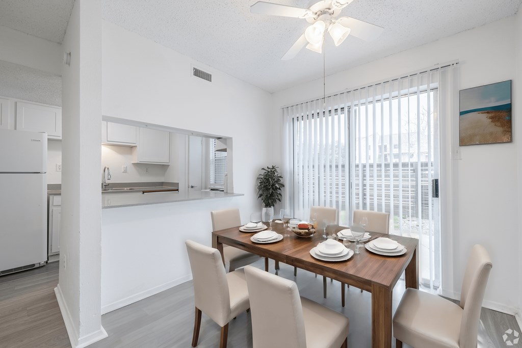the living room and dining area of a apartment with a wooden table and chairs