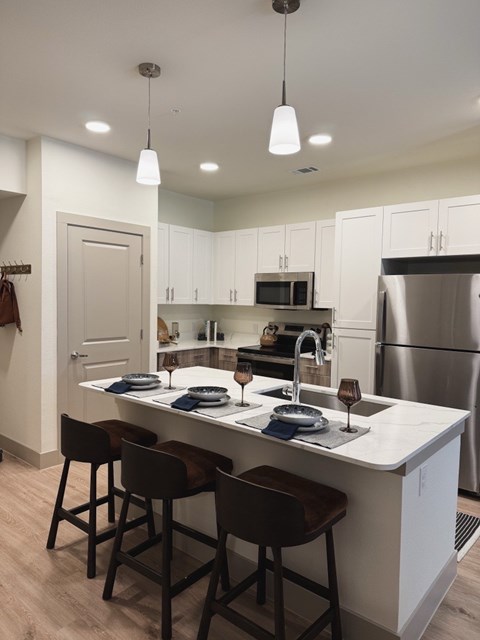 A kitchen with white cabinets and a white island with a sink.