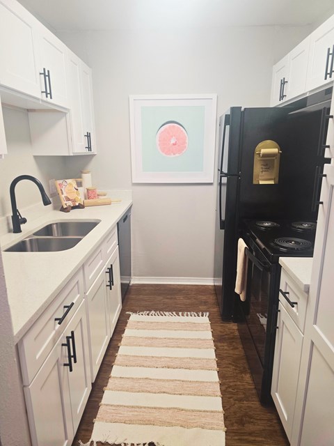 a small kitchen with white cabinets and a black refrigerator