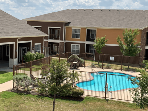 A small pool is surrounded by a fence and a building.