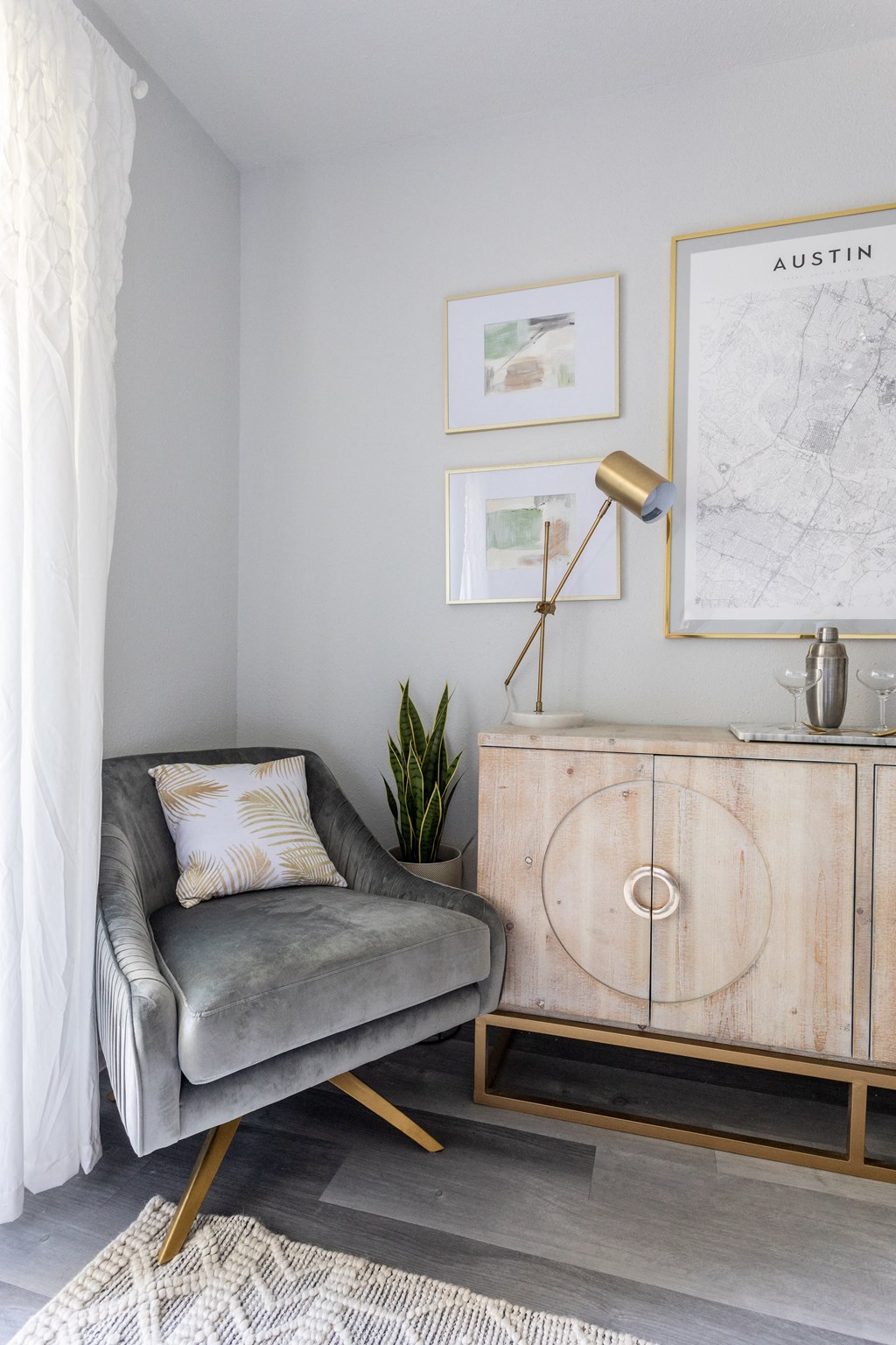 a living room with a gray couch and a cabinet and a lamp