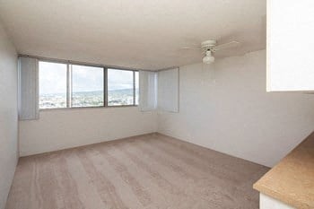 an empty living room with a ceiling fan and windows