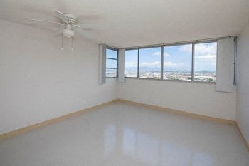 an empty room with a ceiling fan and three windows