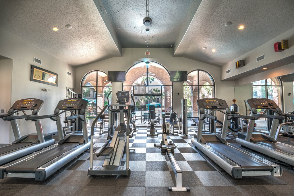 a gym with cardio machines and weights on a checkered floor