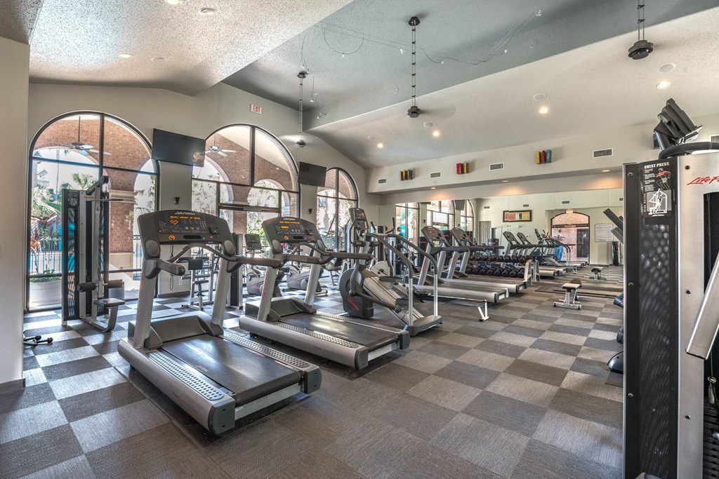 a gym with cardio machines and weights on a checkered floor