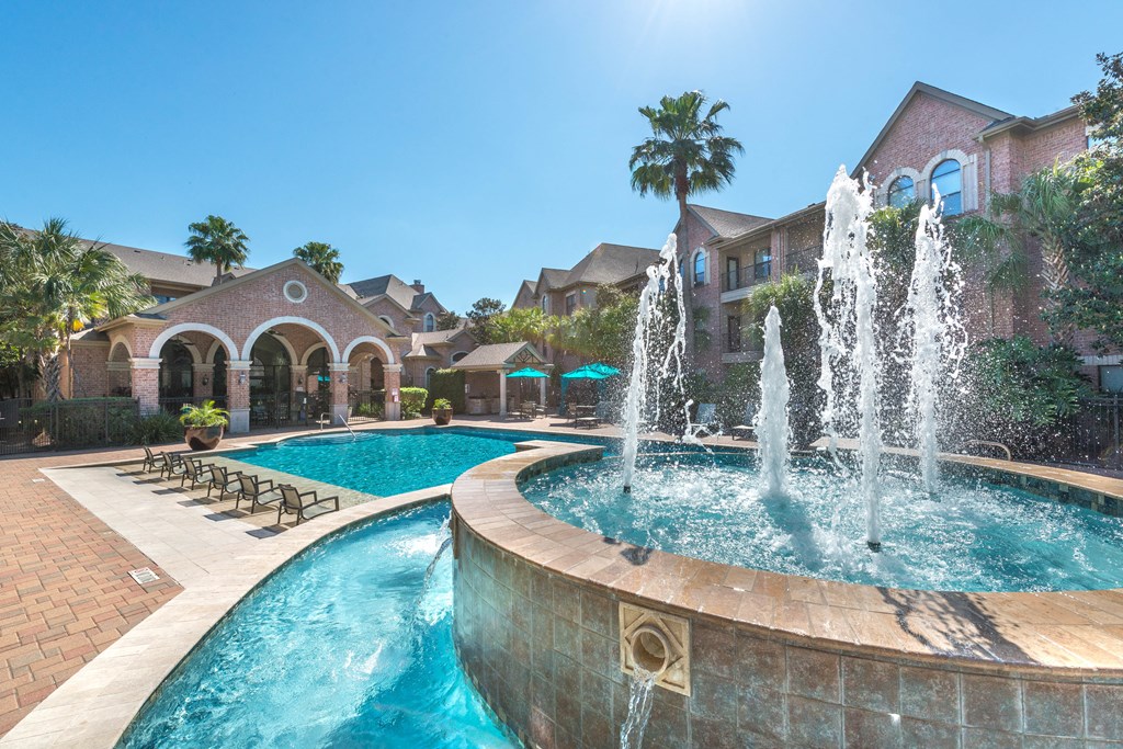 a large pool with water jets in front of a house