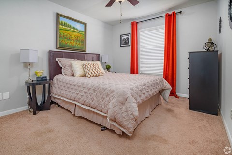 a bedroom with a bed and a window with red curtains