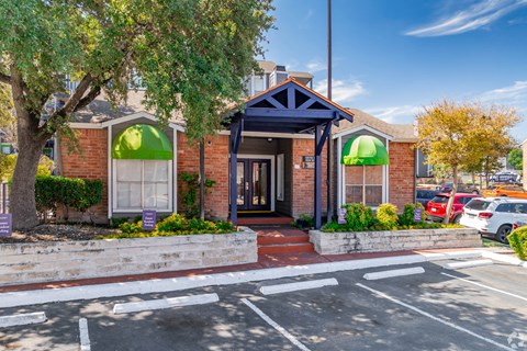 the front of a red brick building with green umbrellas