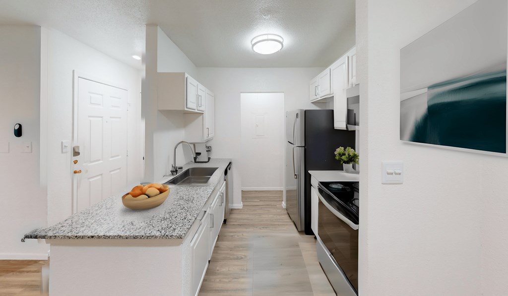 a kitchen with white cabinets and a counter top with a bowl of fruit