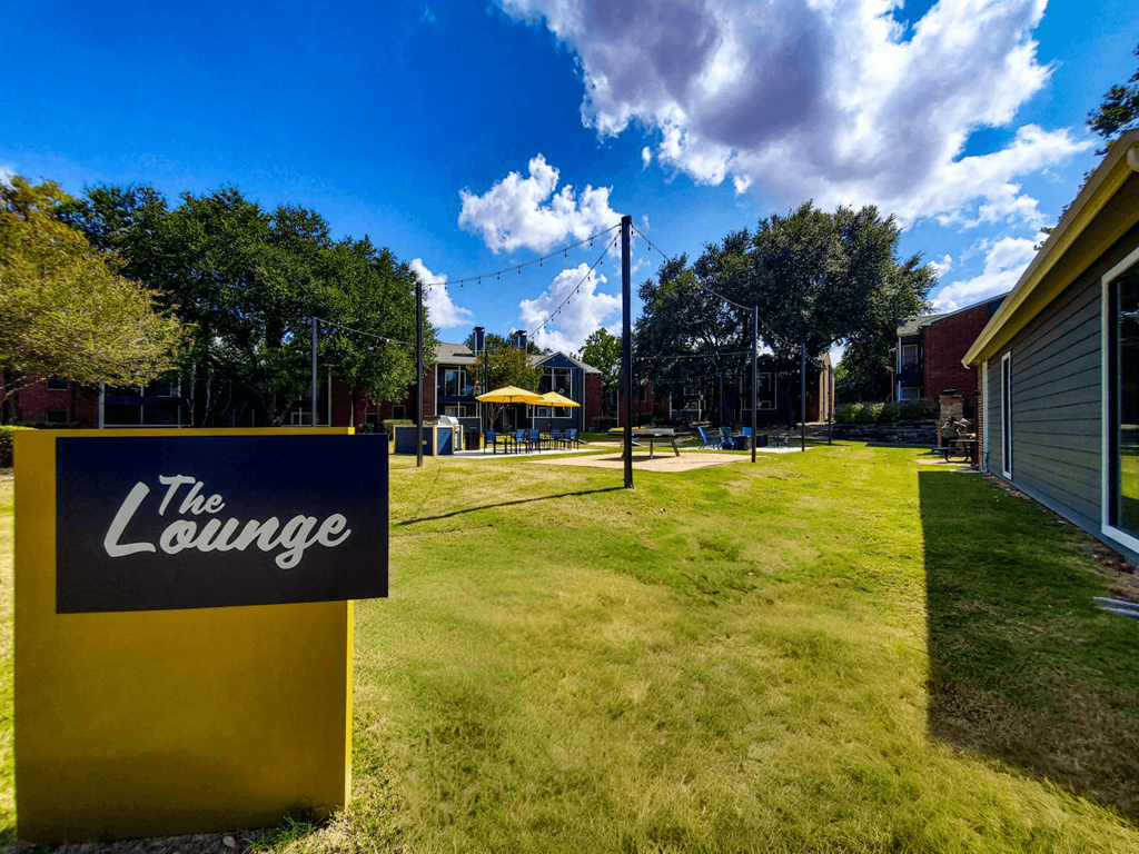 a yard with a sign for the lounge in front of a building