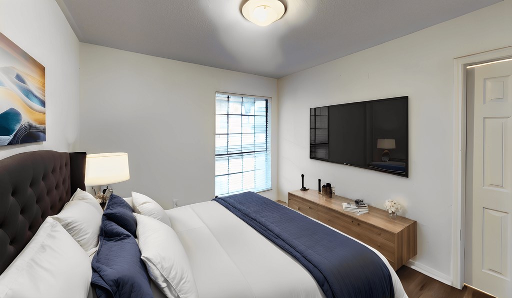 a bedroom with a large bed and a tv on the wall